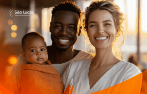 Família sendo atendida em casa por uma profissional de saúde e pai com bebê no colo, mãe ao lado, todos sorrindo e tranquilos. A profissional está uniformizada, com kit de coleta visível, em um ambiente residencial iluminado.